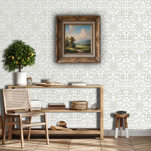 May include: A room with a wooden shelf, chair, and small table. A framed landscape painting hangs on the wall above the shelf. The wall has a repeating geometric pattern. A small potted tree with lemons sits on the shelf.