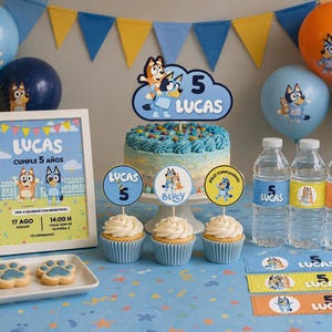 Puede incluir: Decoración de fiesta de cumpleaños con temática de Bluey. Incluye una tarta, cupcakes, globos, botellas de agua y un cartel enmarcado que dice "Lucas cumple 5 años". La combinación de colores es azul, amarillo y naranja.