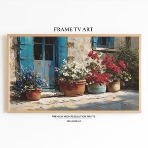May include: A framed print of a European-style scene. The artwork depicts a weathered building with blue shutters and doors, and several potted plants with red, white, and blue flowers. The text "FRAME TV ART" and "PREMIUM HIGH RESOLUTION PRINTS RED ADMIRALS" are visible.