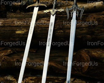 May include: Three decorative swords with silver blades and detailed handles are displayed on a wooden surface. The swords have intricate gold and black designs, with the text "IronForgedUs" visible. The blades are angled, highlighting their sharp edges.