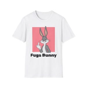 Op de afbeelding: Wit T-shirt met een cartoon Bugs Bunny die de middelvinger opsteekt. De afbeelding staat op een roze achtergrond met de tekst "Fugs Bunny" in zwarte letters eronder.