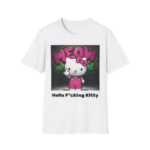 Op de afbeelding: Wit T-shirt met een cartoonkat met een roze strik en outfit, die de middelvinger opsteekt. Het woord "MEOW" staat in roze graffiti boven de kat, en de tekst "Hello F*cking Kitty" staat eronder.