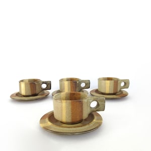 May include: Set of four ceramic espresso cups and saucers. Each cup and saucer features vertical stripes in shades of brown and tan with a gold accent stripe. The cups have a square handle.