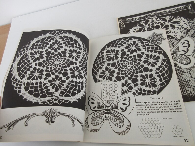 K&ouml;nnte beinhalten: Ein schwarz-wei&szlig;es Buch mit H&auml;kelmustern. Das Buch zeigt eine Nahaufnahme einer geh&auml;kelten Deckchen, ein Schmetterlingsdesign und Anleitungen zum H&auml;keln eines "Hex-Motivs".