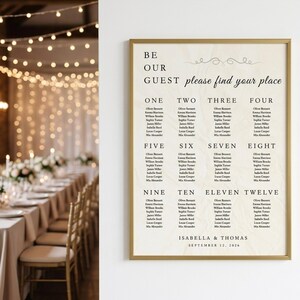 May include: A framed seating chart with a gold border. The text reads "BE OUR GUEST please find your place." Names are listed under numbers one through twelve. The names are for Isabella & Thomas, September 12, 2026.