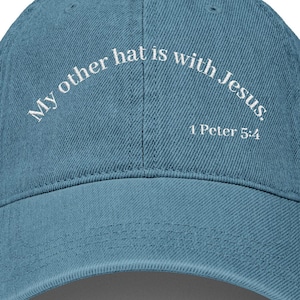 May include: A denim blue baseball cap with the text "My other hat is with Jesus, 1 Peter 5:4" in white lettering. The hat has a curved brim and a classic six-panel design.