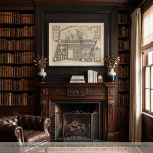 May include: A framed black and white architectural garden map print hanging above a dark wood fireplace mantel. The mantel features two white and blue vases with dried botanicals, a stack of books, and a small gold clock on a dark wall.