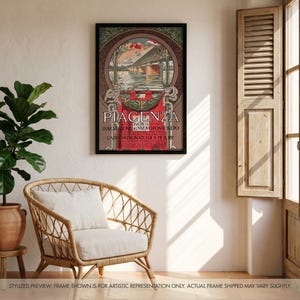 May include: Framed vintage poster featuring the word "PIACENZA" in large letters. The poster has an Art Nouveau style with a bridge illustration and Italian text. The poster is displayed on a white wall next to a wicker chair and a potted plant.