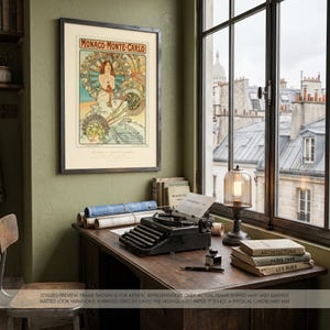 May include: A framed vintage poster titled "Monaco-Monte Carlo" hangs on a green wall. The poster features an Art Nouveau design with a woman and floral elements. A desk with a typewriter, books, and a lamp sits near a window overlooking a cityscape.