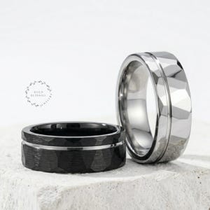 May include: Two rings with a faceted geometric surface texture. One ring is matte black with a thin silver-toned centre groove, and the other is polished silver-toned with a matching centre groove. The text BOLD BLING CO. JEWELRY is visible.