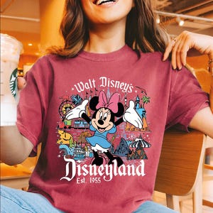 A woman wearing a red t-shirt with a Disney-themed graphic of Minnie Mouse and Disneyland.