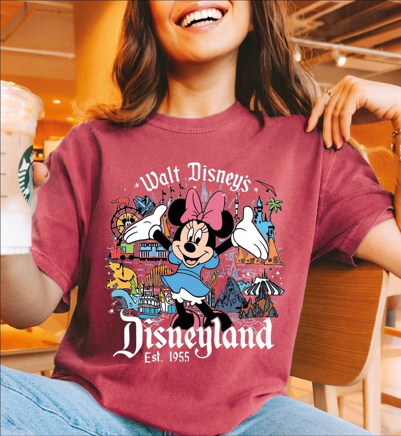 A woman wearing a red t-shirt with a Disney-themed graphic of Minnie Mouse and Disneyland.
