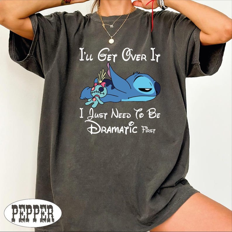 A person wearing a gray t-shirt with a cartoon character and text printed on it.