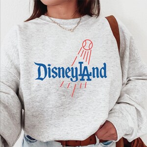 A person wearing a gray sweatshirt with the text "Disneyland" printed on it.