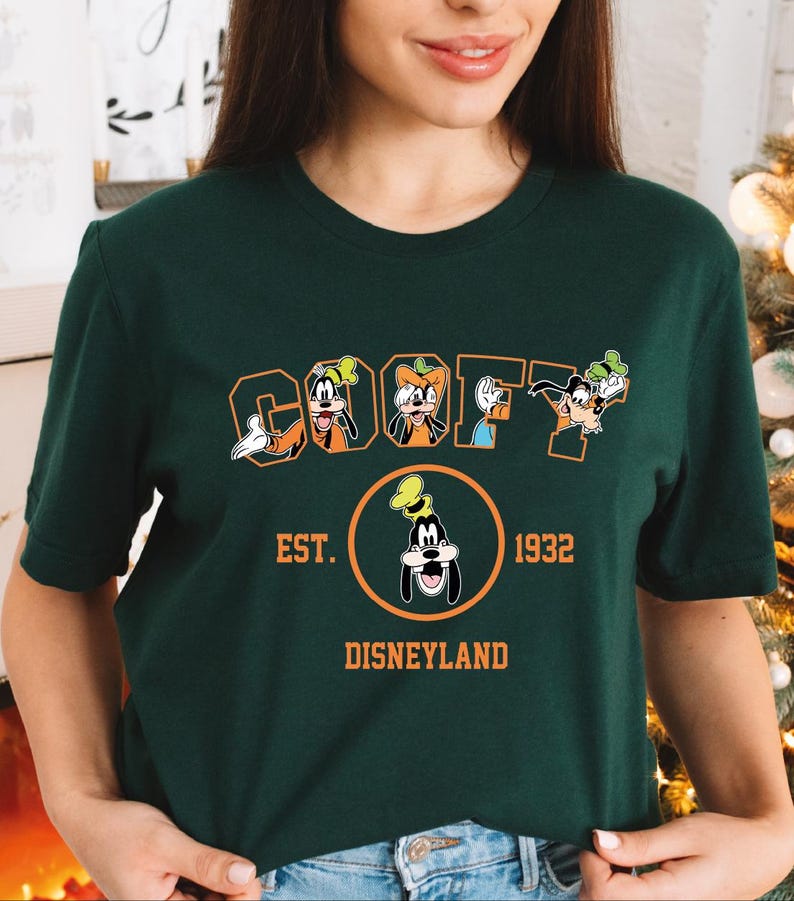 A woman wearing a green t-shirt with a graphic design featuring the characters Goofy and Mickey Mouse.