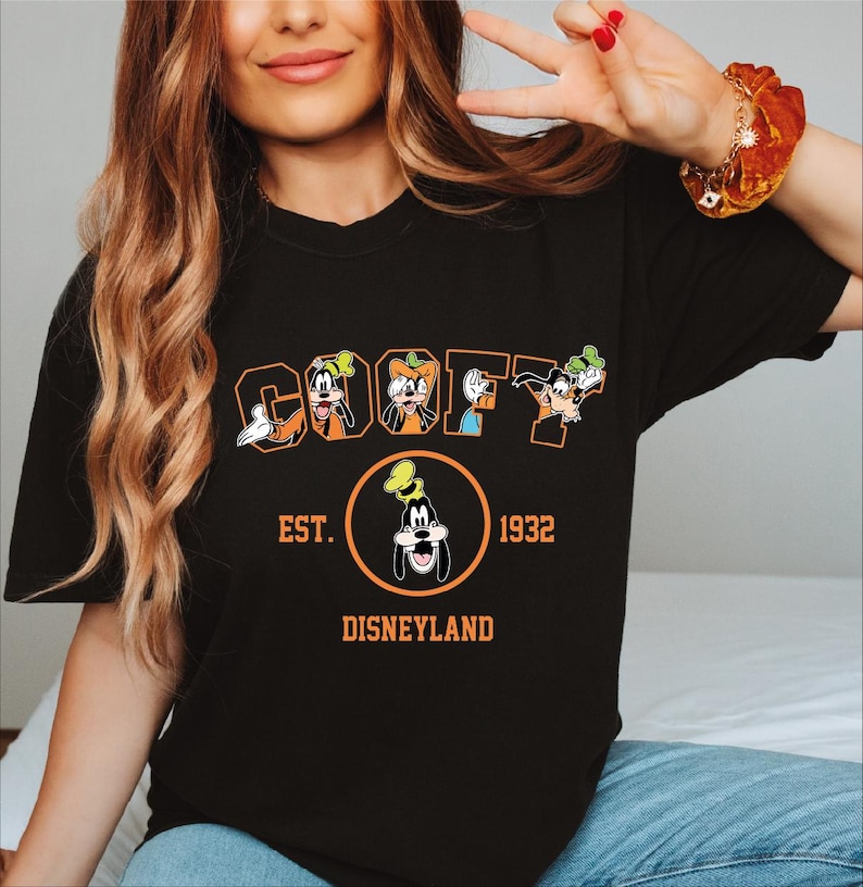 A woman wearing a black t-shirt with a graphic design featuring the character Goofy from Disneyland.