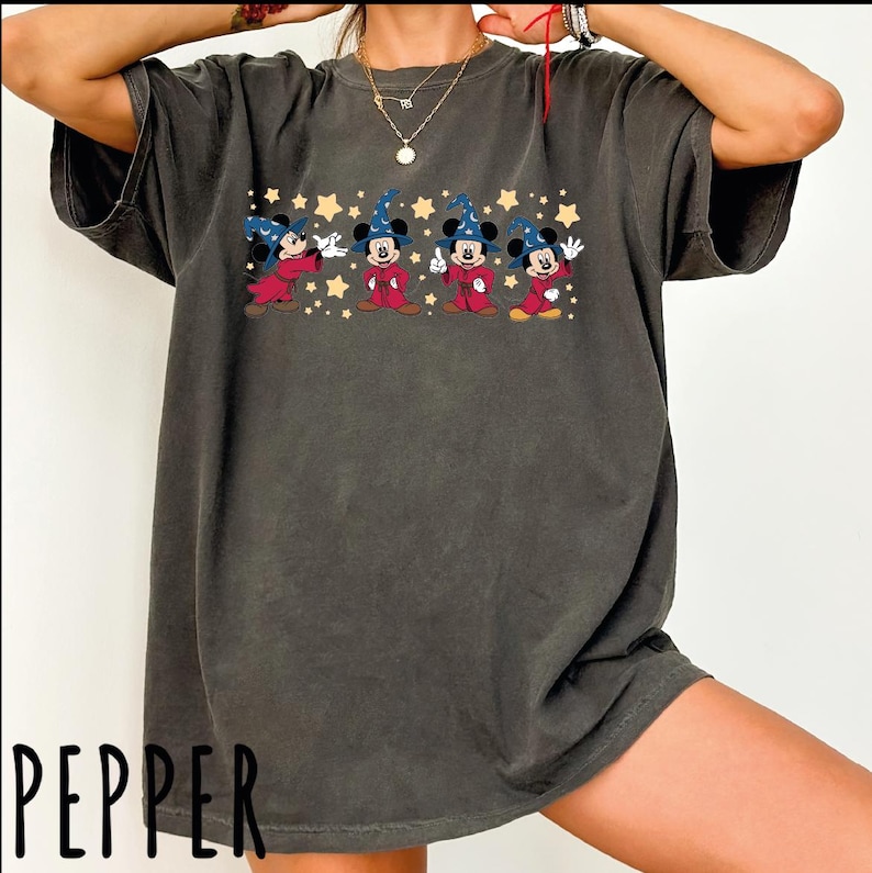 A person wearing a gray t-shirt with a graphic of Mickey Mouse and four other characters, along with stars and a red string.