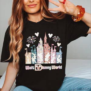 A woman wearing a black t-shirt with a graphic design of a Disney castle and fireworks.