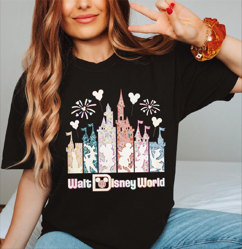 A woman wearing a black t-shirt with a graphic design of a Disney castle and fireworks.