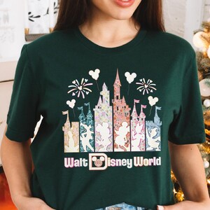 A woman wearing a green t-shirt with a graphic design of Disney World landmarks and characters.
