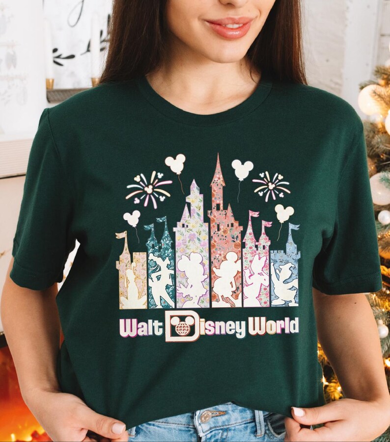 A woman wearing a green t-shirt with a graphic design of Disney World landmarks and characters.
