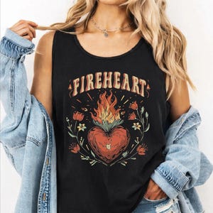 May include: Black tank top with the word "FIREHEART" in a vintage font. The graphic features a flaming heart with floral and botanical accents. The design is in shades of red, orange, and yellow.