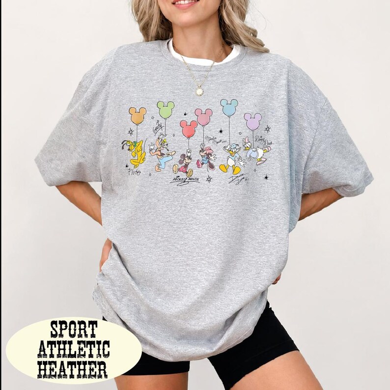 A woman wearing a gray sweatshirt with a graphic of Disney characters and balloons printed on it.
