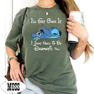 A person wearing a green t-shirt with a cartoon character and text printed on it.