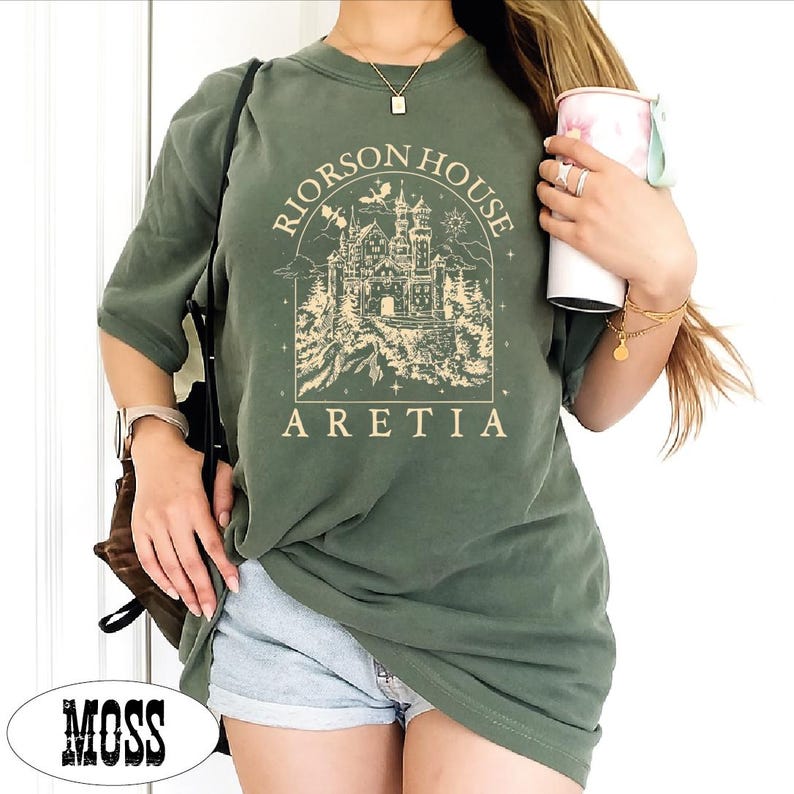 A person wearing a green t-shirt with a graphic design and holding a cup of coffee.