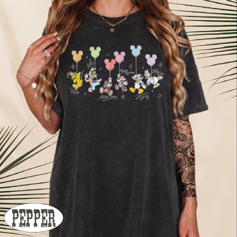 A woman wearing a black t-shirt with a graphic of Disney characters and balloons.