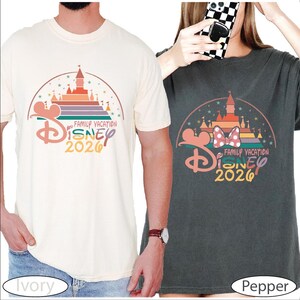 two people wearing Disney-themed t-shirts, one white and one black, with the text "Disney 2020" printed on them.
