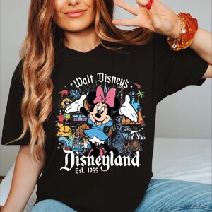 A woman wearing a black t-shirt with a Disney-themed graphic and text.