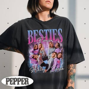 May include: Black t-shirt with a graphic design featuring the word "BESTIES" in a gradient blue and pink font, with the word "Forever" below it. The design includes a photo of several women and the names "Ashley - Sarah".