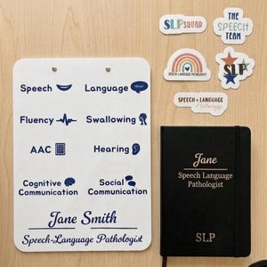 May include: A white clipboard with blue text and icons for speech, language, fluency, swallowing, AAC, hearing, cognitive and social communication, plus the name Jane Smith. Includes a black notebook labeled Jane Speech Language Pathologist and stickers.