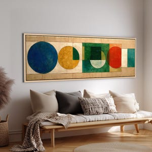 May include: A long rectangular wall art piece featuring a series of geometric shapes including a large blue circle, a yellow circle, a green square, and a red circle set against a textured gold background, all framed in a light wood frame.