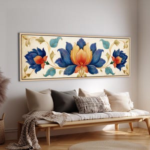 Può includere: Un'opera d'arte murale rettangolare caratterizzata da un design floreale simmetrico con un grande fiore centrale nei toni del giallo, arancione e blu intenso, affiancato da due fiori più piccoli, su sfondo crema in una cornice in legno chiaro.