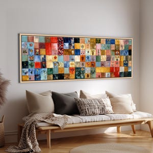 以下が含まれることがあります： 木製のフレームに入った、長方形の大きなアートワーク。アートワークは、それぞれユニークなパターンとデザインを持つ、多数のカラフルな正方形で構成されています。窓の近くにある、枕と毛布が付いた木製のベンチの上に掛けられています。