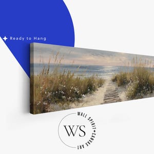 May include: A panoramic canvas print featuring a coastal landscape with a sandy path leading through tall dune grasses toward the ocean at sunset. The sky is painted in soft muted tones of blue and grey. The text Ready to Hang is visible.