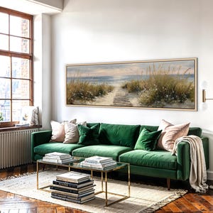 May include: A long, rectangular landscape painting in a light wood frame depicting a sandy beach path leading toward the ocean. The scene features tall dune grasses, soft blue water, and a pale sky, capturing a serene coastal view in a wide format.