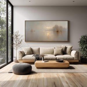 Può includere: Un moderno soggiorno con un ampio divano beige con diversi cuscini, un tavolino in legno e un pouf grigio. Un grande dipinto di paesaggio è appeso sopra il divano. La stanza ha grandi finestre e pavimenti in legno.