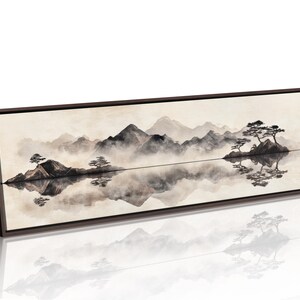 May include: A framed landscape art print featuring a serene mountain scene reflected in calm water. The artwork uses muted tones of gray, black, and beige, with stylized trees and mountains. The frame is dark brown.