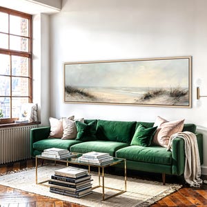May include: A long, horizontal landscape painting in a light wood frame depicting a sandy beach with dunes and tall grasses under a soft, pale sky. The artwork features muted tones of beige, cream, and light blue, capturing a coastal scene.