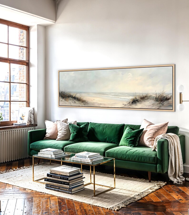 May include: A long, horizontal landscape painting in a light wood frame depicting a sandy beach with dunes and tall grasses under a soft, pale sky. The artwork features muted tones of beige, cream, and light blue, capturing a coastal scene.