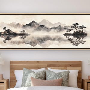 May include: A long, rectangular framed canvas art piece depicting a serene landscape. The artwork features a monochromatic scene of mountains, water, and trees, with reflections in the water. The color palette is primarily black, white, and gray.