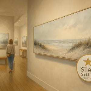 May include: A large horizontal framed canvas painting depicting a coastal beach scene with sand dunes and ocean waves, displayed on a wall. A circular badge with a gold star and the text STAR SELLER on Etsy is positioned in the lower right corner.