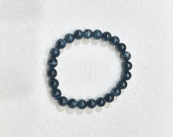 May include: A dark blue beaded bracelet. The bracelet features round, polished beads with a marbled effect. The beads are strung on an elastic band, forming a flexible accessory suitable for wear.