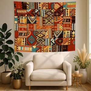 May include: A large, rectangular tapestry with a patchwork design. The tapestry features a variety of geometric and floral patterns in shades of orange, red, blue, and yellow. It hangs above a cream-colored armchair, creating a warm and inviting atmosphere.