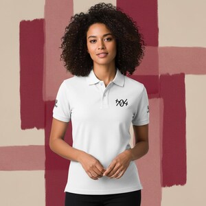 Peut inclure: Polo blanc à manches courtes et col. Le t-shirt porte le numéro "404" en écriture noire sur la poitrine et un petit motif sur la manche gauche. Le fond présente un motif en blocs de couleurs dans les tons de rouge et beige.