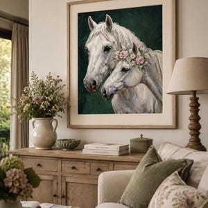 Op de afbeelding: Een ingelijste print met twee witte paarden, waarvan &eacute;&eacute;n met een bloemenkrans, tegen een donkergroene achtergrond. De lijst is lichtbruin. Het kunstwerk wordt in een woonkamer getoond.