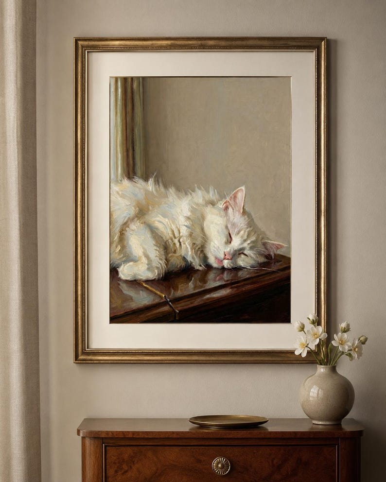 May include: A framed painting depicting a white cat asleep on a dark wooden surface. The artwork is in a gold frame, displayed above a wooden chest of drawers. A small vase with white flowers and a gold plate are on the chest.